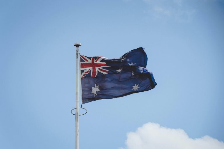 Australian national flag waving on a flagpole against a clear blue sky in Perth.